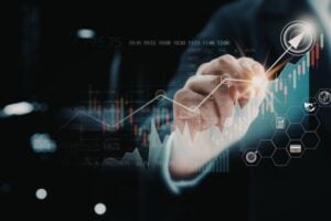 fundsforNGOs - 2026-06-05T153221277 - Funds for Companies Close-up of a businessperson's hand pointing at a glowing stock chart with a rising arrow and digital icons.