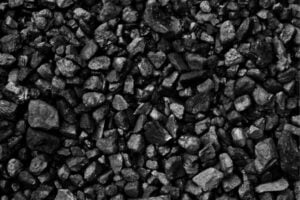 fundsforNGOs - Funds for Companies Close-up of small, irregular dark gray rocks (coal-like gravel) scattered across a surface.