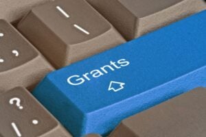 Blue keyboard key labeled 'Grants' with a small graduation cap icon among brown keys.